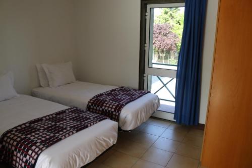 um quarto de hotel com duas camas e uma janela em HI Guarda - Pousada de Juventude na Guarda