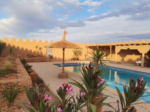 a resort with a swimming pool and an umbrella at Ksar Montana Hôtel, Chambres piscine in Taforhalt