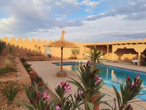 a resort with a swimming pool and an umbrella at Ksar Montana Gîtes, Chambres piscine in Taforhalt