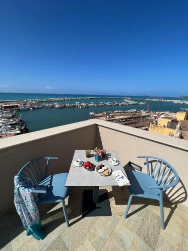 a table and chairs on a balcony with a view of the water at RoccaRegina Hotel in Sciacca