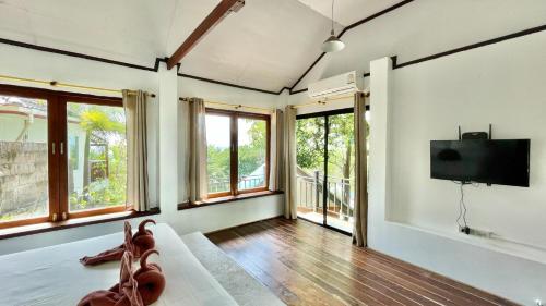 a living room with a tv and some windows at P.D. Beach Resort in Koh Tao