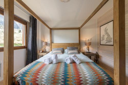 um quarto com uma cama grande e um cobertor colorido em Les Eaux Cristallines de Bredannaz, unique vue lac 6p LLA Selections by Location lac Annecy em Doussard