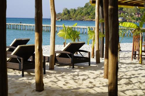 a group of chairs on a beach with a pier at WHITE SAND ARK RESORT in Koh Rong Island