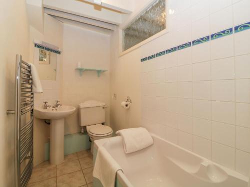 a bathroom with a sink and a toilet and a bath tub at Blackberry Cottage in Kingsbridge