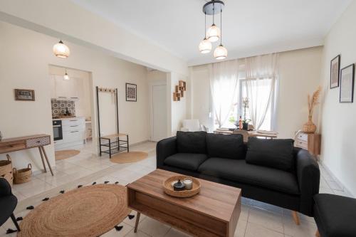 a living room with a black couch and a table at Irena House by RentalsPro - Dionisiou Halkidiki in Zográfos