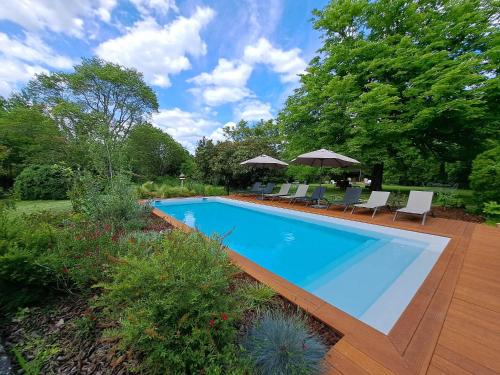 a swimming pool in a yard with chairs and umbrellas at NAMASTE COTTAGE in Issigeac
