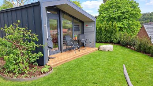 een klein huis met een terras en een tafel in een tuin bij Sauerland-Tinyworld - Ihr Tiny Ferienhaus im Sauerland am Diemelsee in Diemelsee