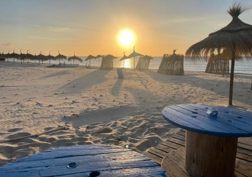 um pôr-do-sol numa praia com guarda-sóis e o oceano em Renaissance em Bou Ficha