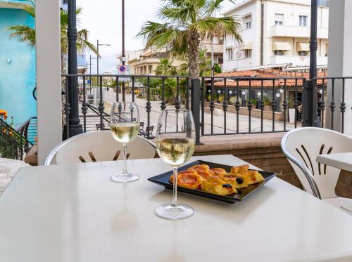 stół z dwoma kieliszkami wina i talerzem jedzenia w obiekcie Hotel Greta B&B w Rimini