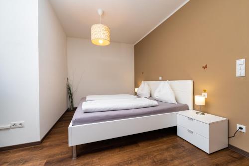 una camera con letto bianco e comodino di Appartament Emma a Brunico