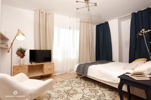 a bedroom with a bed and a tv and a chair at Chic Concept Studio in Bucharest