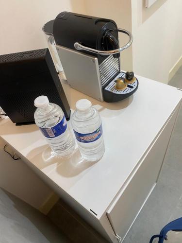 - deux bouteilles d'eau assises sur un bureau blanc dans l'établissement Apart Nissa Bella Massena / Vieux Nice, à Nice