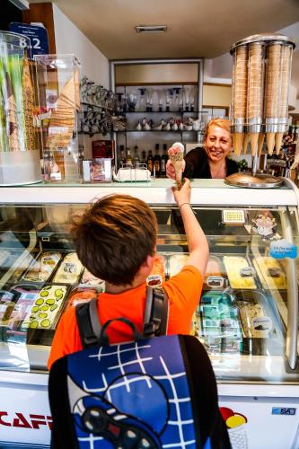 a woman standing behind a counter with a man eating ice cream at Pension Café Maier in Golling an der Salzach