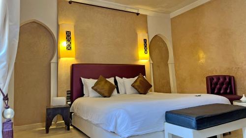 a bedroom with a large white bed and a chair at Riad Pourpre Medina in Marrakesh