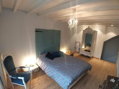 ein Schlafzimmer mit einem Bett, einem Stuhl und einem Spiegel in der Unterkunft Gîte La Poule Bleue in Charavines