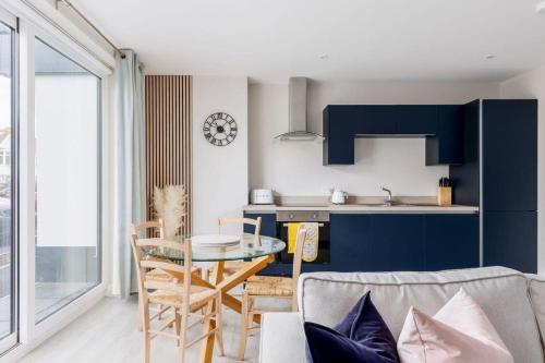 a living room with a table and a kitchen at Modern 2 bed, cliff top & parking, F6 in Southbourne