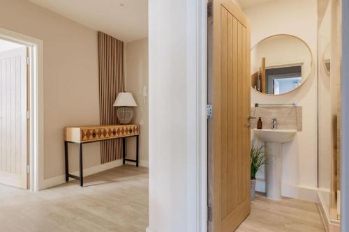 a hallway with a bathroom with a sink and a mirror at Modern 2 bed, cliff top & parking, F6 in Southbourne