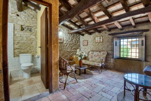 a bathroom with a toilet and a chair and a table at Canapost in Peratallada