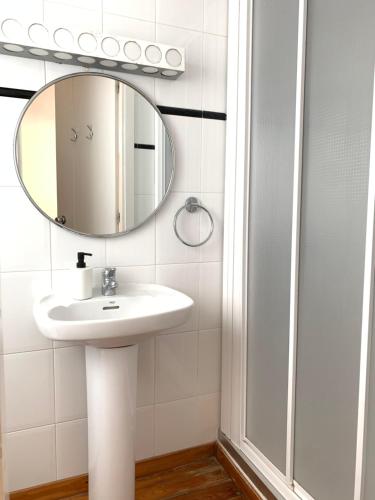 a white bathroom with a sink and a mirror at Dúplex Deli in Cadaqués