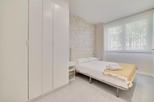 a white bedroom with a bed and a window at Apartamentos Pamplona Confort by Clabao in Pamplona
