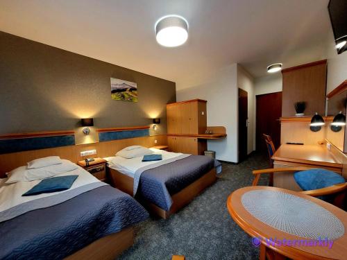 a hotel room with two beds and a table at Olimpia Resort & SPA in Szczyrk
