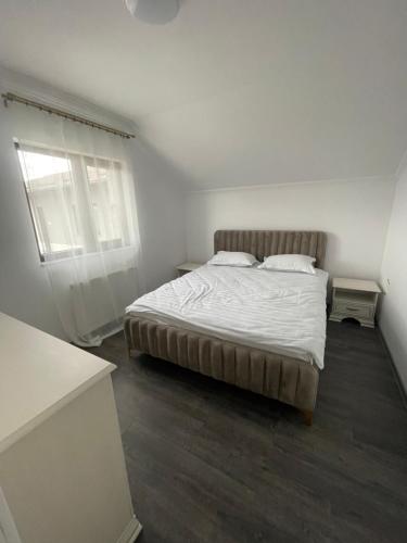 a white bedroom with a bed and a window at Eroilor II Apartament in Suceava