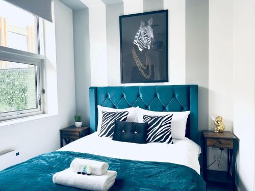 a bedroom with a bed with a blue headboard at KVM - Lavish Style Apartment - Modern 2 Bedroom Apartment in Bayard FREE Parking - KVM Lavish Style Apartment by KVM Stays in Peterborough