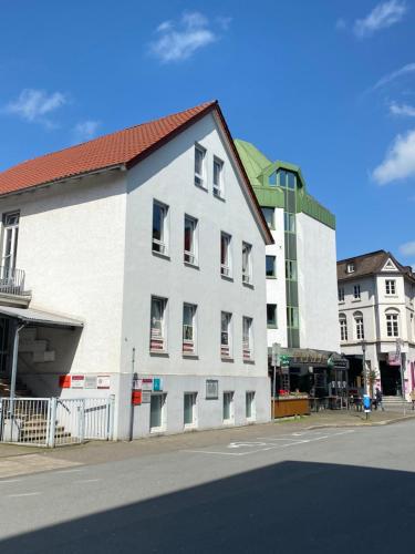 un bâtiment blanc avec un toit rouge dans une rue dans l'établissement CITYNA Apartment Bielefeld, à Bielefeld