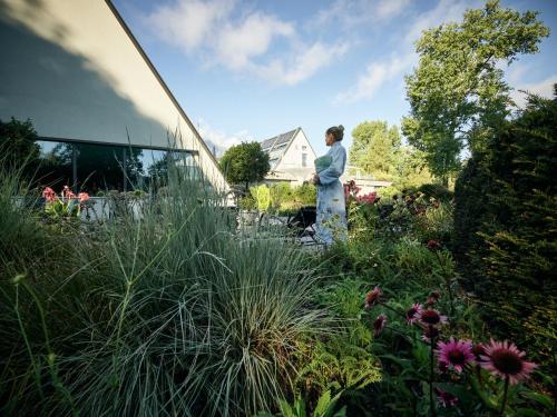 a woman standing in a garden next to a house at Deltapark Vitalresort Seevillen in Thun