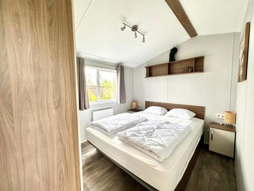 シント・マールテンにあるChalet 539 op Recreatiepark De Wielenのベッドルーム1室(白いシーツ付きのベッド1台、窓付)
