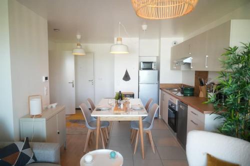 une cuisine avec une table et des chaises dans une pièce dans l'établissement Chez Elsa, confortable apt neuf avec parking privé, à Saint-Valery-sur-Somme