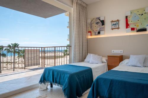een slaapkamer met 2 bedden en een balkon met uitzicht op de oceaan bij AT111 Vistas frontales a la playa la Paella in Torredembarra