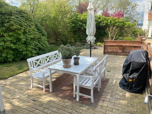a white table with two chairs and an umbrella at Knasborg Ferieboliger in Ålbæk
