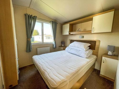 a small bedroom with a bed and a window at Brilliant 8 Berth Caravan With Decking At Haven Caister Beach Ref 30055p in Great Yarmouth