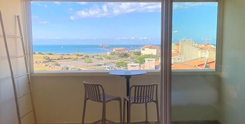 a table and two chairs in front of a window at Hôtel La Grande Conque in Cap d'Agde