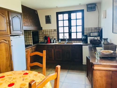 une cuisine avec une table et un réfrigérateur blanc dans l'établissement Gites grande capacité à saint-chély-d’aubrac, à Regaussou