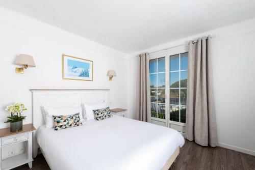 a white bedroom with a large bed and a window at Hôtel Beau Site - Cap d'Antibes in Antibes