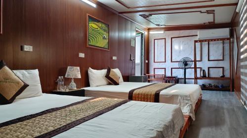 a hotel room with two beds and wooden walls at Tam Coc Melody Homestay in Ninh Binh