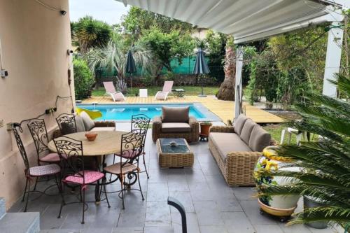 um pátio com uma mesa e cadeiras ao lado de uma piscina em Holiday house in the city-center of Antibes with a private pool em Antibes