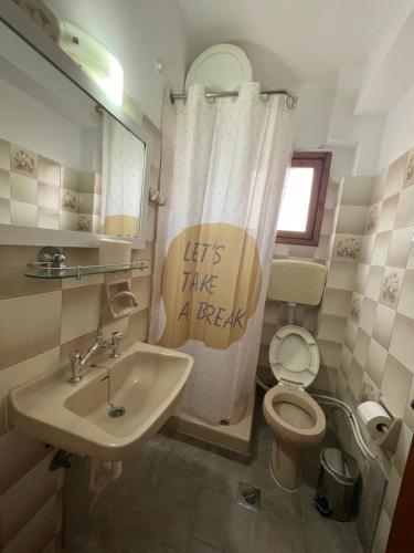 a bathroom with a sink and a toilet and a shower curtain at The Beehive 2 in Mytilini