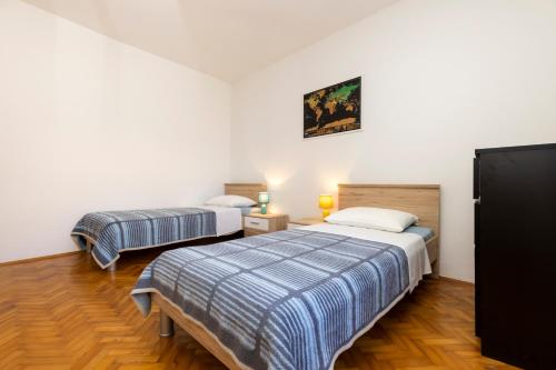 twee bedden in een kamer met witte muren en houten vloeren bij J&T - app J&T in Mali Lošinj