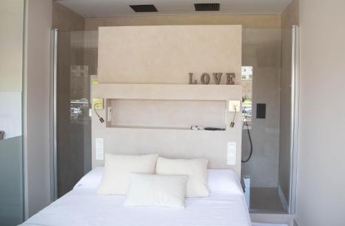a bedroom with a white bed with a love sign above it at Astorga suites in Astorga