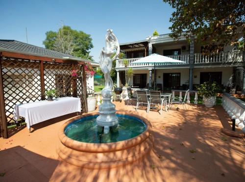 a fountain in a courtyard with a table and chairs at Golden Candle Guest House in Roodepoort