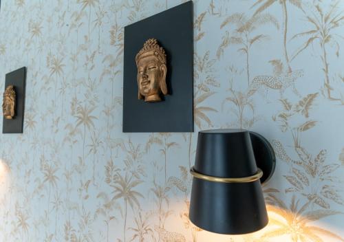 a lamp and a bust on a wall with wallpaper at Nouvel Hôtel in Paris