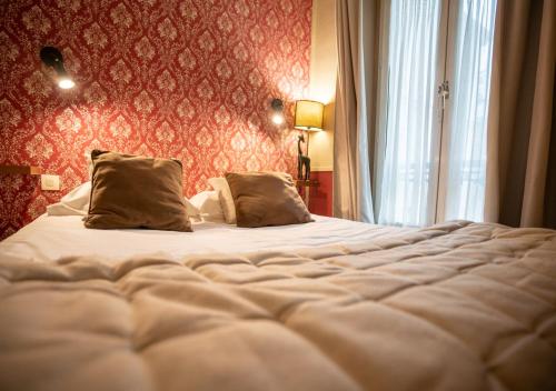 a large bed with two pillows in a bedroom at Nouvel Hôtel in Paris