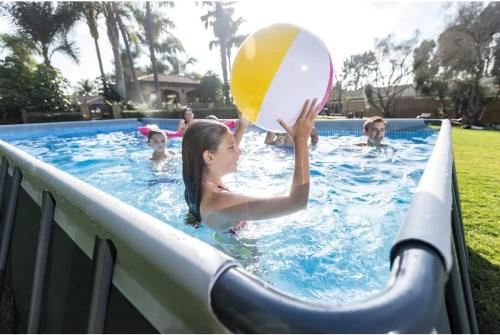 une fille jouant avec un ballon de plage dans une piscine dans l'établissement La Vougerotte - Terrasse Vue Montagnes, à Vougy