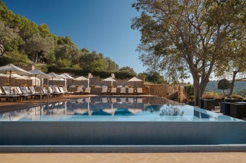 uma piscina com cadeiras e guarda-sóis num resort em Son Brull Hotel & Spa em Pollença