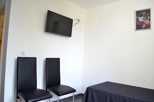 twee zwarte stoelen naast een muur met een tv bij Zwei Raben Pension in Mainz