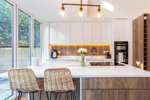 a kitchen with white cabinets and a counter with stools at Family home close to Bournemouth town centre in Bournemouth
