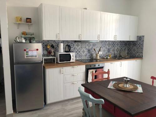 una cucina con armadi bianchi, tavolo e frigorifero di Via Puccini 217 a Viareggio